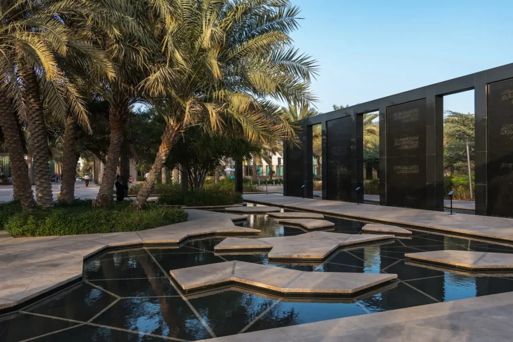 Elegant landscape designing services in Dubai by RCi Red Chillies Interiors LLC, featuring palm trees, modern walkways, geometric water features, and lush greenery